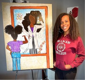 A smiling Black woman with long hair, wearing a red Hillman College sweatshirt, standing next to an easel holding a large painting. The painting shows a Black girl with her back to the viewer, looking at a painting (or mirror?) with an adult Black woman in a white lab coat holding a chemistry beaker with science symbols all around her.